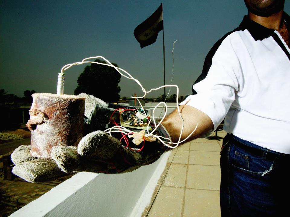 A member of the Iraqi Civil Defense unit holding an IED in one hand.