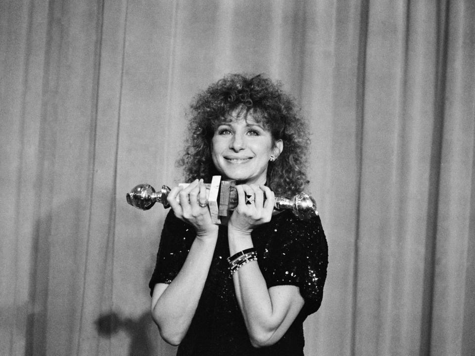 Barbra Streisand poses with her Golden Globe awards for best director (musical or comedy) and best actress (musical or comedy) in 1984.