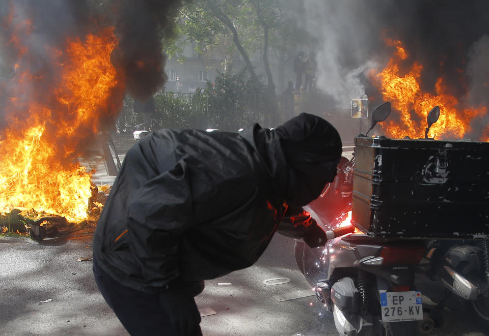 A protestor lights a motorbike on fire during a yellow vest demonstration in Paris, Saturday, April 20, 2019. French yellow vest protesters are marching anew to remind the government that rebuilding the fire-ravaged Notre Dame Cathedral isn't the only problem the nation needs to solve. (AP Photo/Michel Euler)