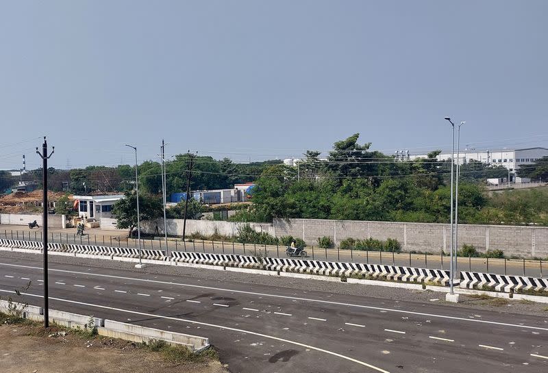 Men ride their motorbikes past a closed plant of India Foxconn unit, near Chennai