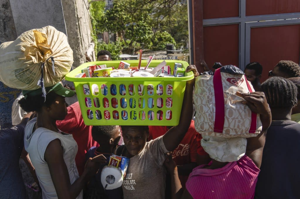 Neighbors pass in and out of a passageway as others erect a metal gate as protection against gangs, in the Petion-Ville neighborhood of Port-au-Prince, Haiti, Saturday, April 20, 2024. (AP Photo/Ramon Espinosa)