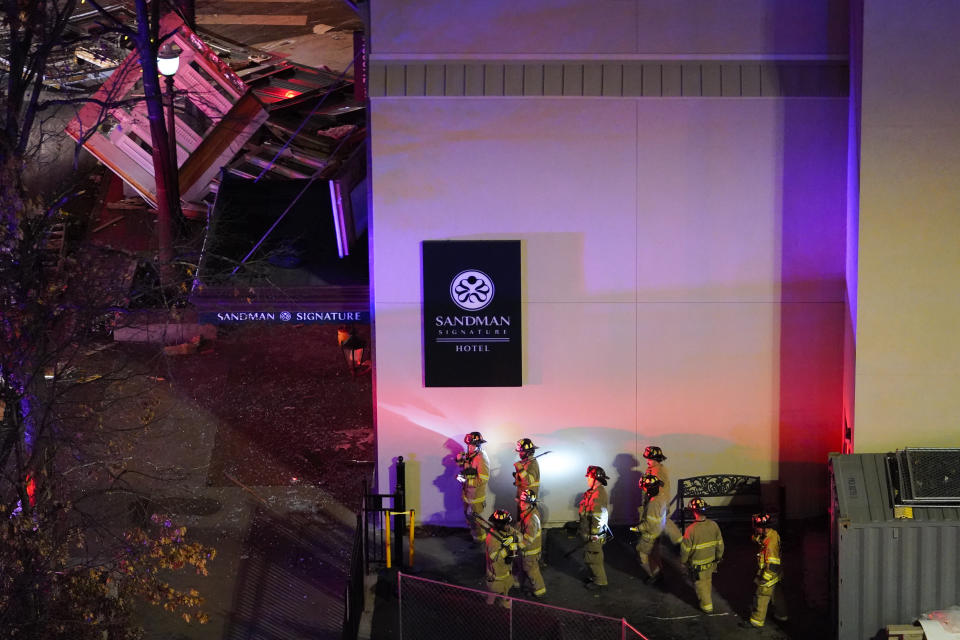 Damage, top left, is seen as firefighters exit the Sandman Signature hotel following an explosion earlier in the day, Monday, Jan. 8, 2024, in Fort Worth, Texas. (AP Photo/Julio Cortez)