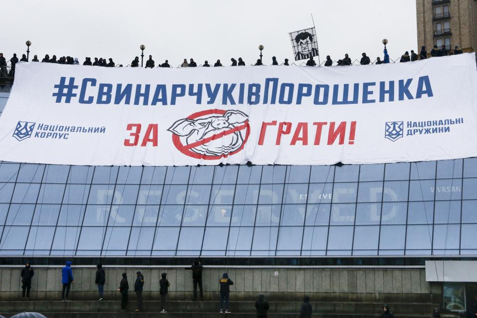 Far-right demonstrators brandish flares as they display a large banner reading "Poroshenko’s pigs to jail" during a rally against corruption in Kiev, Ukraine, Saturday, March 16, 2019. (AP Photo/Efrem Lukatsky)