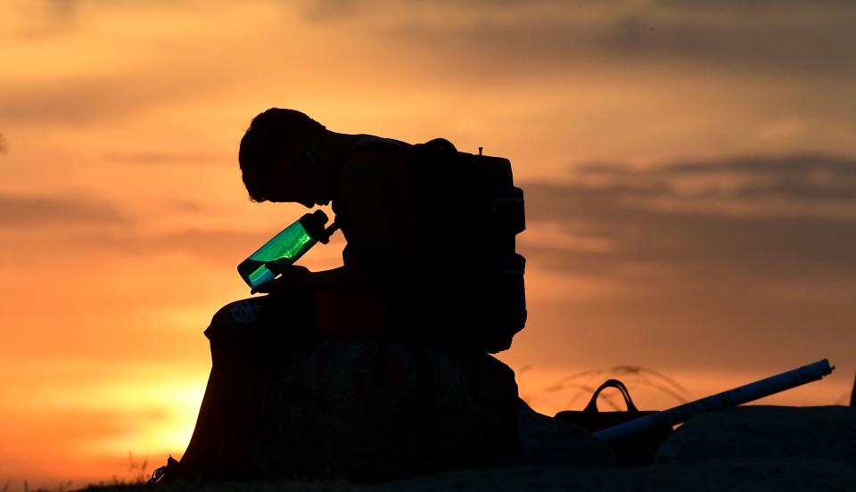 A child looks at his water bottle as the sun sets on June 15, 2021 in Los Angeles, California as temperatures soar in an early-season heatwave. (Frederic J. Brown/AFP via Getty Images)