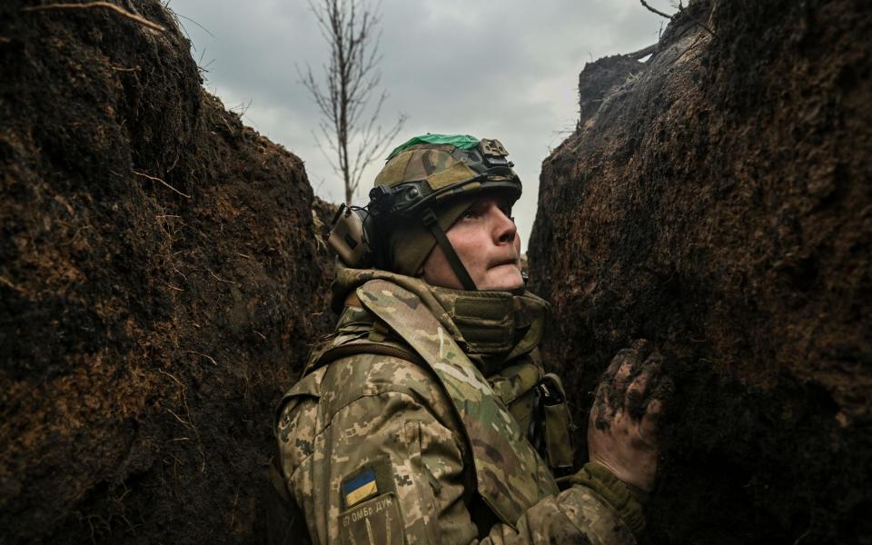 A Ukrainian solder takes cover in a trench near Bakhmut - ARIS MESSINIS/AFP