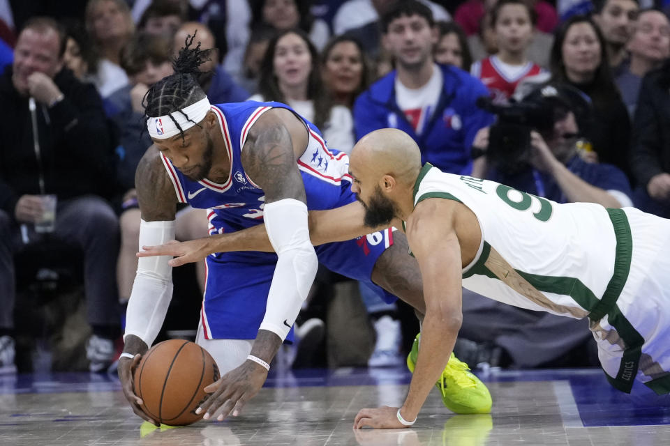 Philadelphia 76ers' Robert Covington, left, and Boston Celtics' Derrick White reach for a loose ball during the first half of an NBA basketball game, Wednesday, Nov. 15, 2023, in Philadelphia. (AP Photo/Matt Slocum)