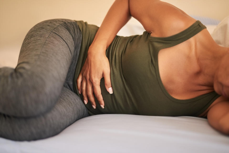 A stock image of a woman grabbing her abdomen in pain