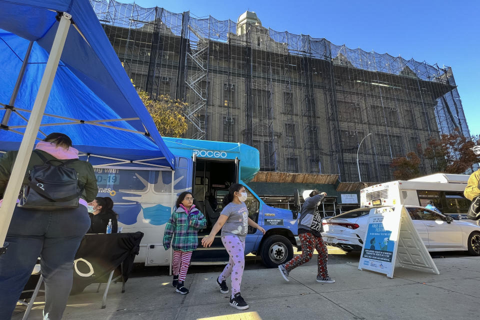 Children walk outside of a mobile vaccine unit after getting the first dose of their COVID-19 vaccine, outside P.S. 277, Friday, Nov. 5, 2021, in the Bronx borough of New York. (AP Photo/Eduardo Munoz Alvarez)