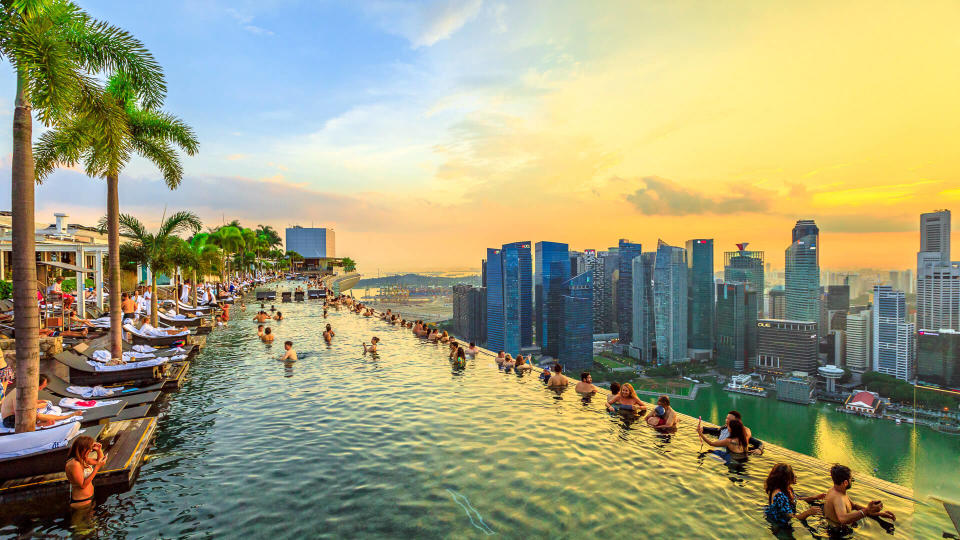 Singapore - May 3, 2018: Infinity Pool at sunset of Skypark that tops the Marina Bay Sands Hotel and Casino from rooftop of La Vie Club Lounge on 57th floor.