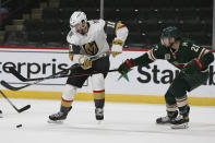 Minnesota Wild's Carson Soucy (21) and Vegas Golden Knights' Nicolas Roy (10) go after the puck in the second period of an NHL hockey game Monday, March 8, 2021, in St. Paul, Minn. (AP Photo/Stacy Bengs)