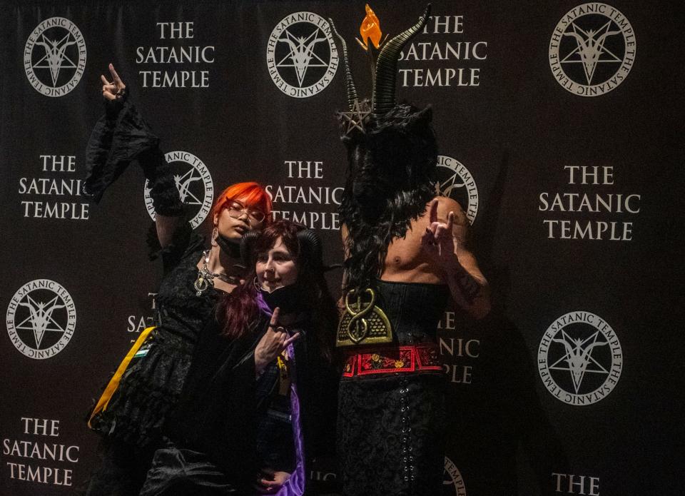 Emma Yama, left, and Prestinne Geiravör Hel, ordained Ministers of Satan through The Satanic Temple, pose with a person wearing a goat mask at SatanCon in Boston, Mass., on April 28, 2023.