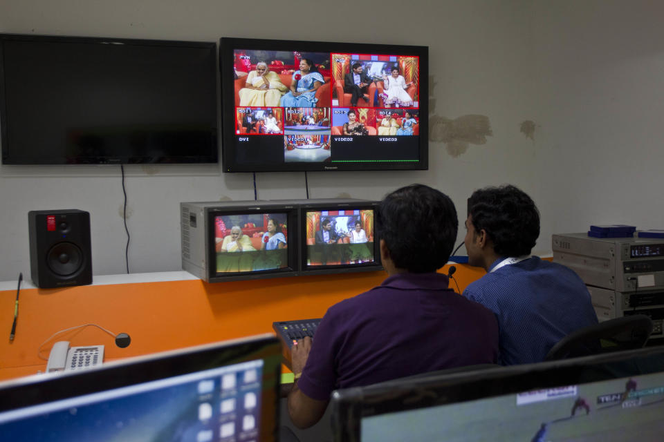 In this July 26, 2013 photo, employees monitor TV screens showing a talk show on Shagun TV, at itsstudio in Noida, India. Indians are obsessed with weddings and obsessed with reality television. Now Shagun TV, a new television channel headquartered in a sprawling suburb of India's capital, is hoping it has found a can't-miss idea — merging the two into a 24-hour matrimonial TV station.(AP Photo/Tsering Topgyal)