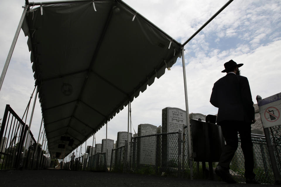 In this July 2, 2019 photo, a man walks past a temporary tent to shield visitors from the elements as they wait to pray at the gravesite of Rabbi Menachem M. Schneerson in the Queens borough of New York. Men and women, young and old, make their way from around the city, the country and the world to this unassuming site, the burial place of Rabbi Menachem Mendel Schneerson, to pay their respects to the life and teachings of the revered Jewish leader of the Chabad-Lubavitch movement who died twenty-five years ago in June 1994. (AP Photo/Seth Wenig)