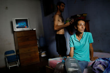 Yaneidi Guzman, 38, sits on her mother-in-law's bed as her husband, Jorge Perez, stands behind her in Caracas, Venezuela, March 31, 2018. REUTERS/Carlos Garcia Rawlins