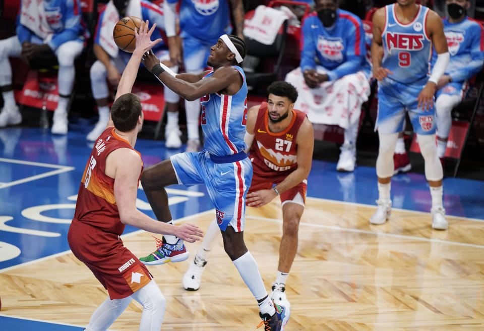 Brooklyn Nets guard Caris LeVert (22) goes for a layup as Denver Nuggets center Nikola Jokic (15) and guard Jamal Murray (27) defend during the second quarter of an NBA basketball game Tuesday, Jan. 12, 2021, in New York. (AP Photo/Kathy Willens)