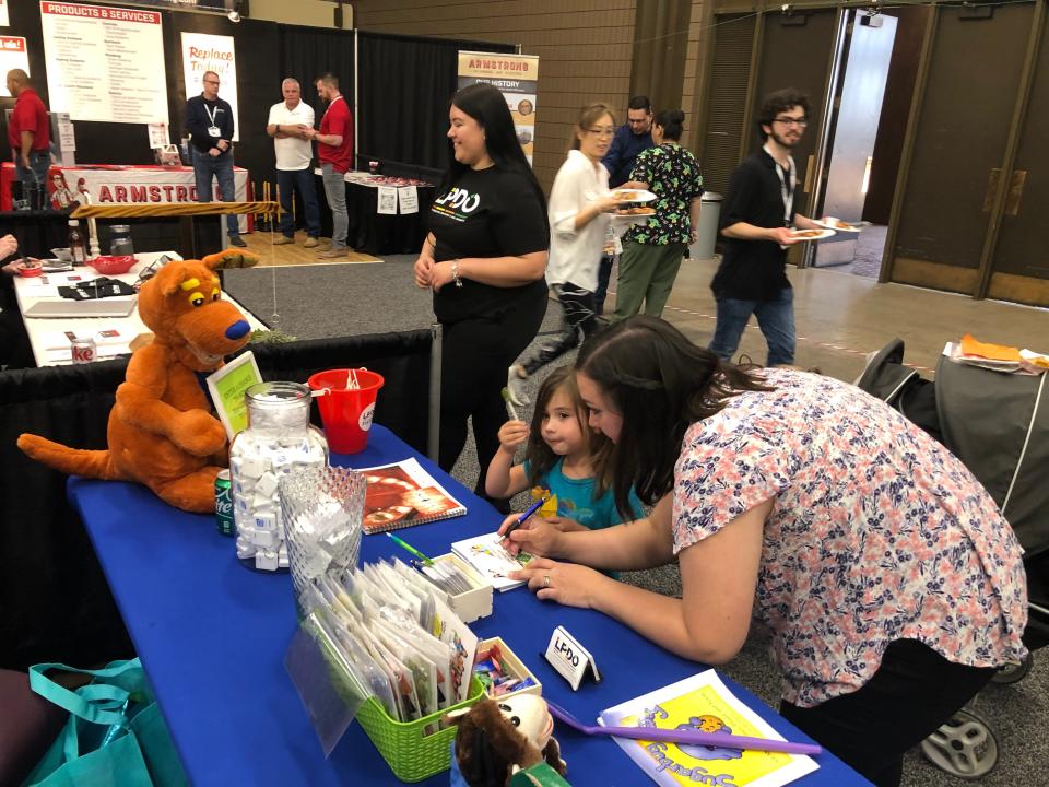 Four-year-old Addi Wilbanks, center, enjoyed a sugar-free apple-flavored sucker as her mother, Gini Wilbanks, filled out a card at the Lubbock Pediatric Dentistry &amp; Oral Surgery booth Thursday at the Lubbock Business Expo.