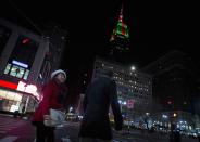 People walk past the Empire State Building in Herald Square as it is lit up in Christmas color lights on Christmas Day in New York, December 25, 2013. REUTERS/Carlo Allegri (UNITED STATES - Tags: SOCIETY CITYSCAPE)