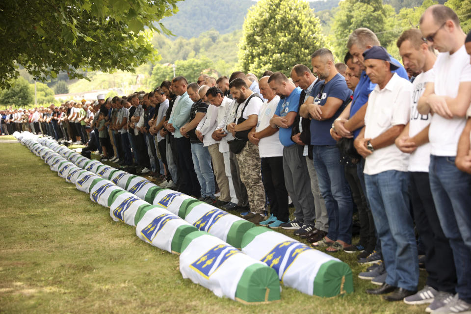 Bosnian muslim men pray next to the coffins containing the remains of 50 newly identified victims of the Srebrenica Genocide, in Potocari, Monday, July 11, 2022. Fifty newly identified victims were honored and reburied Monday in Bosnia as thousands gathered to commemorate the anniversary of the 1995 Srebrenica massacre, Europe’s only acknowledged genocide since the Holocaust. (AP Photo/Armin Durgut)