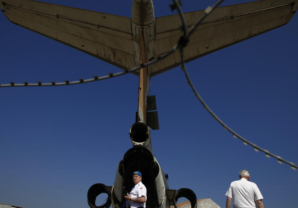 Canadian veteran soldiers who served with the United Nations Peacekeeping force on a war-divided Cyprus, look at an abandoned passenger aircraft, at the derelict Nicosia airport located inside the UN-controlled buffer zone on the capital's outskirts on Tuesday, March 18, 2014. A gutted Cyprus Airways Trident passenger jet a stone’s throw away from the terminal serves a reminder of the fierce battles that had raged there in July, 1974. Advancing Turkish forces had tried to seize the strategically important airport on the capital’s western outskirts, hours in to their invasion of Cyprus that was triggered by a coup aimed at uniting the island with Greece. Canadian soldiers then serving with the United Nations Peacekeeping force in Cyprus _ or UNFICYP _ helped repel the advance. Since then, it’s been the force’s headquarters midway through a 180 kilometer (112 mile) buffer zone that splits this ethnically divided island into a breakaway Turkish Cypriot north and a internationally recognized, Greek Cypriot south. (AP Photo/Petros Karadjias)