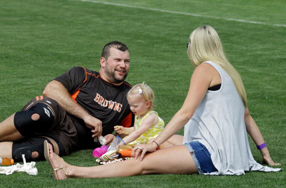 Cleveland Browns tackle Joe Thomas sits with his wife, Annie, and daughter, Logan, after the opening practice at an NFL football training camp, Saturday, July 26, 2014, in Berea, Ohio. (AP Photo/Mark Duncan)