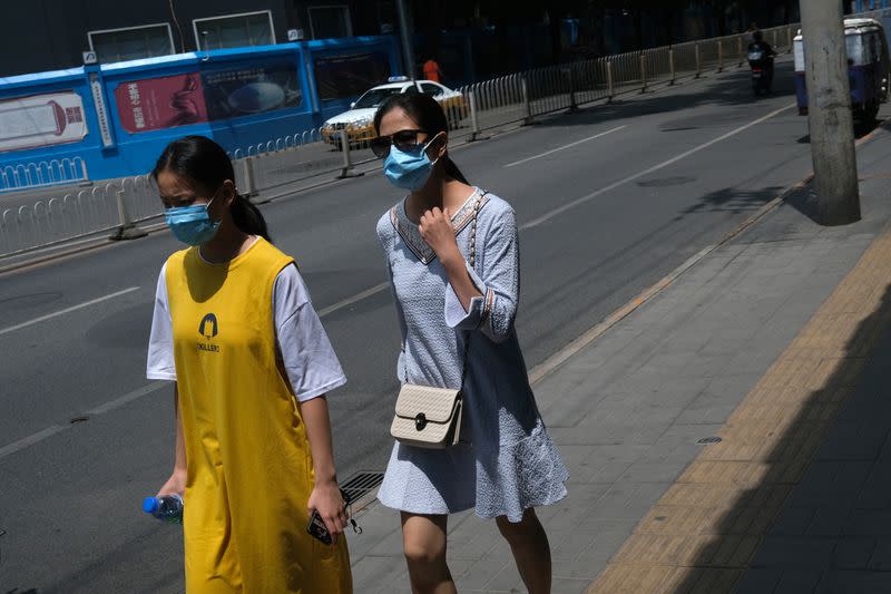 People wearing face masks walk on a street, following the outbreak of the coronavirus disease (COVID-19), in Beijing