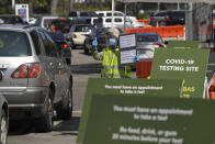 Workers direct cars as they wait in line for coronavirus testing at Dodger Stadium Tuesday, July 14, 2020, in Los Angeles. (AP Photo/Mark J. Terrill)