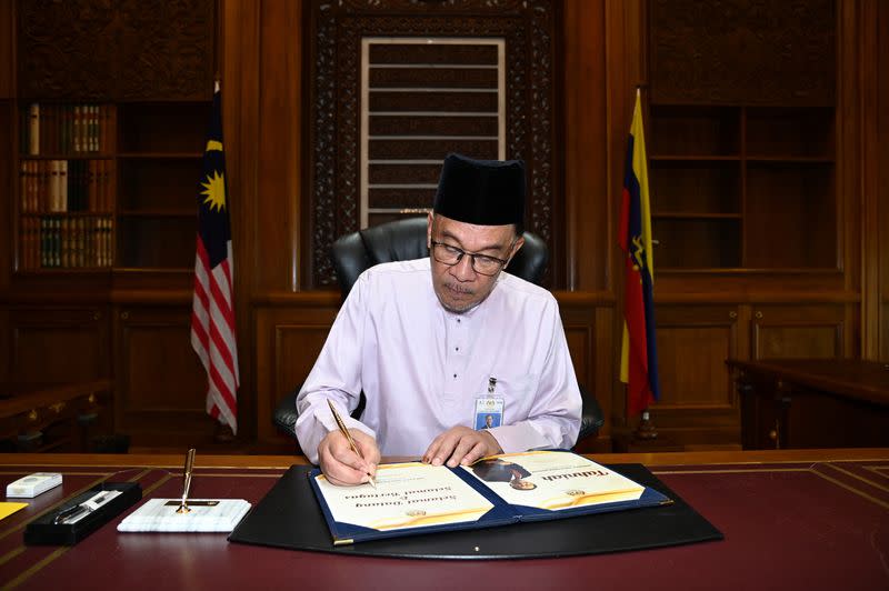 Malaysia's newly appointed Prime Minister Anwar Ibrahim signing a document at Putrajaya