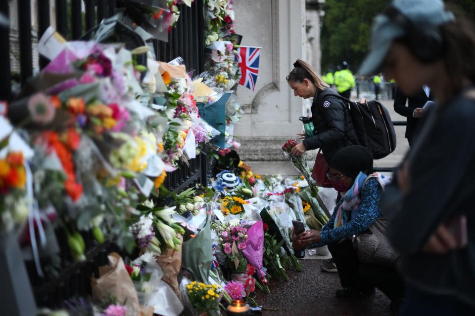 People lay flowers as they gather to pay their respects outside Buckingham Palace in London on September 9, 2022, a day after Queen Elizabeth II died at the age of 96. (Getty Images)