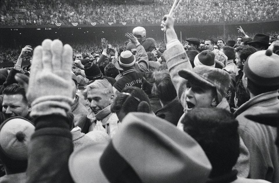 The Lions' Joe Schmidt is carried off field by fans after winning the NFL championship in 1957.