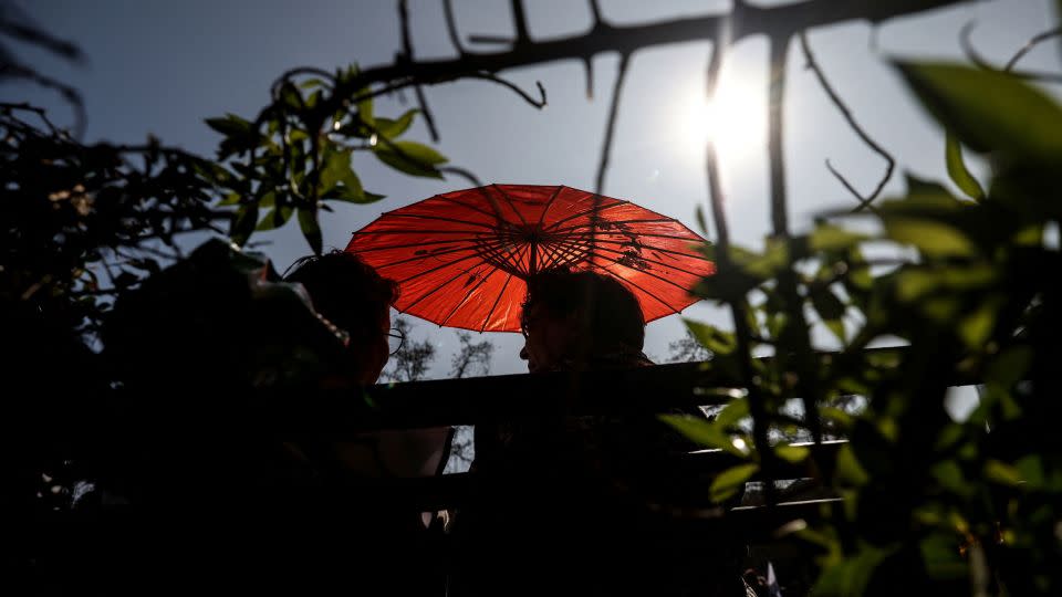 A woman uses an umbrella during an unusual winter period heatwave in Santiago, Chile, August 3, 2023.  - Ivan Alvarado/Reuters