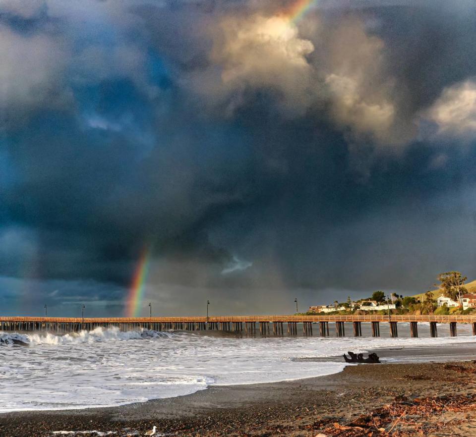 A rainbow breaks through storm clouds over Cayucos just after sunrise on Wednesday, Feb. 7, 2024. The pier was closed on Tuesday after sustaining damage from the weekend storms.