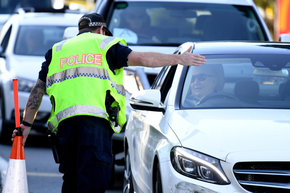 A police officer directs a car for further inspection at a check point on the Queensland-NSW border in Coolangatta on the Gold Coast. 