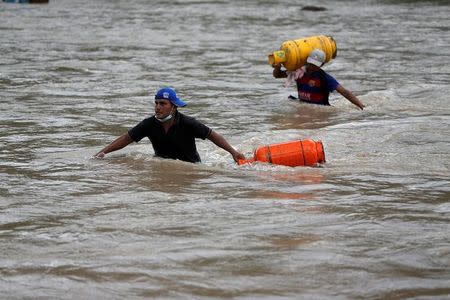 Men walk in a river with their belongings after flooding and mudslides caused by heavy rains in Mocoa, Colombia April 2, 2017. REUTERS/Jaime Saldarriaga