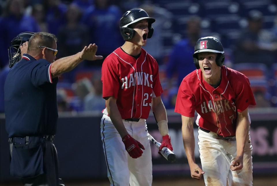 Hiland's Colin Coblentz, right, and Caden Coblentz, center, after scoring the game-tying run against Calvert during the seventh inning of an OHSAA Division IV state semifinal baseball game at Canal Park, Thursday, June 8, 2023, in Akron, Ohio.
