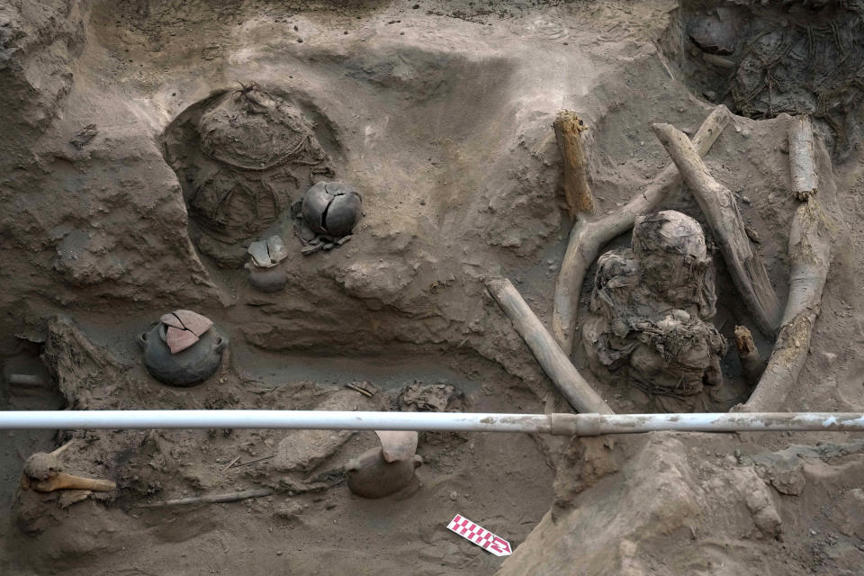 Ancient vessels lay next to an illegal water pipe running through the site where archaeologists uncover bones and vessels discovered by workers who were digging a natural gas line for the company Calidda in the district of Carabayllo on the outskirts of Lima, Peru, Friday, Sept. 22, 2023. Eight burial offerings from the pre-Inca Ychsma culture have been identified by archeologists so far, according to lead archeologist Jesus Bahamonde. (AP Photo/Martin Mejia)