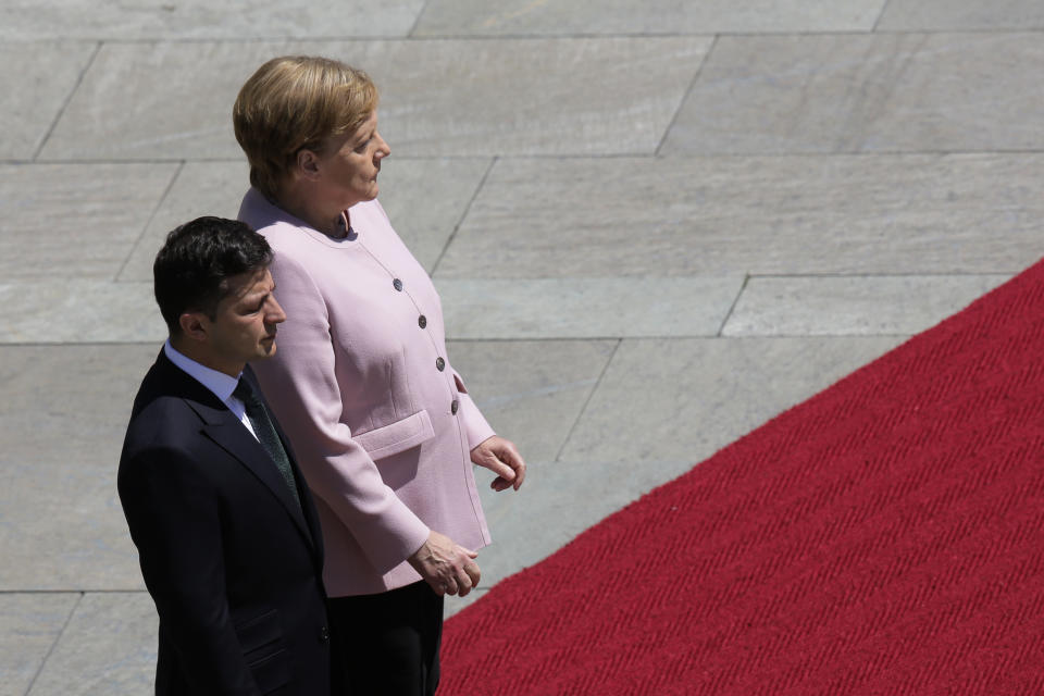 German Chancellor Angela Merkel, right, and Ukrainian President Volodymyr Zelenskiy, left, listen to the national anthems during the welcoming ceremony, prior to a meeting at the chancellery in Berlin, Germany, Tuesday, June 18, 2019. (AP Photo/Markus Schreiber)