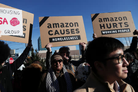 Demonstrators hold signs during a protest against Amazon in the Long Island City section of the Queens borough of New York, U.S., February 14, 2019. REUTERS/Shannon Stapleton