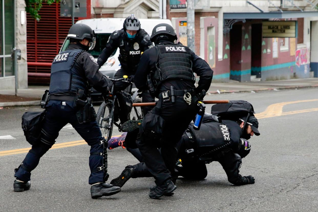 Police officers tackle a demonstrator to the floor at Seattle's CHOP zone, where Independent reporter Andrew Buncombe was arrested (AFP via Getty)