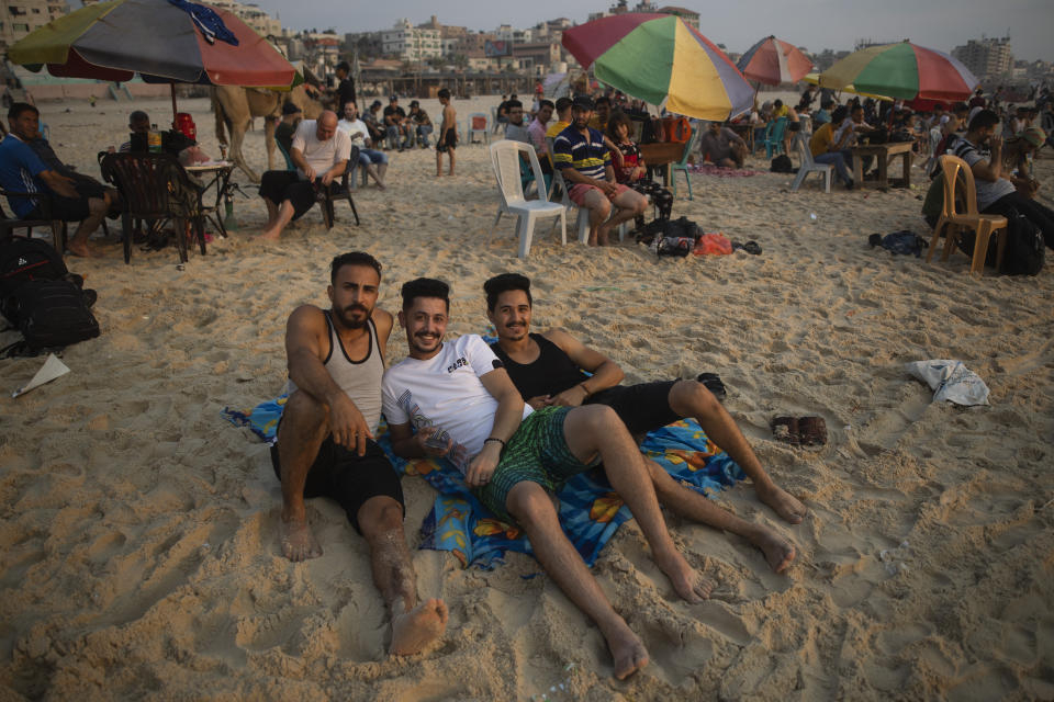 Three Palestinians pose for a photograph while enjoying a summer day setting on the beach of Gaza City, Friday, July. 30, 2021. (AP Photo/Khalil Hamra)
