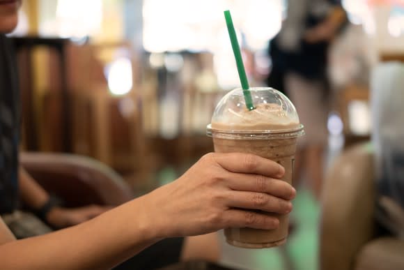 Woman holding a cup of store-bought iced coffee.