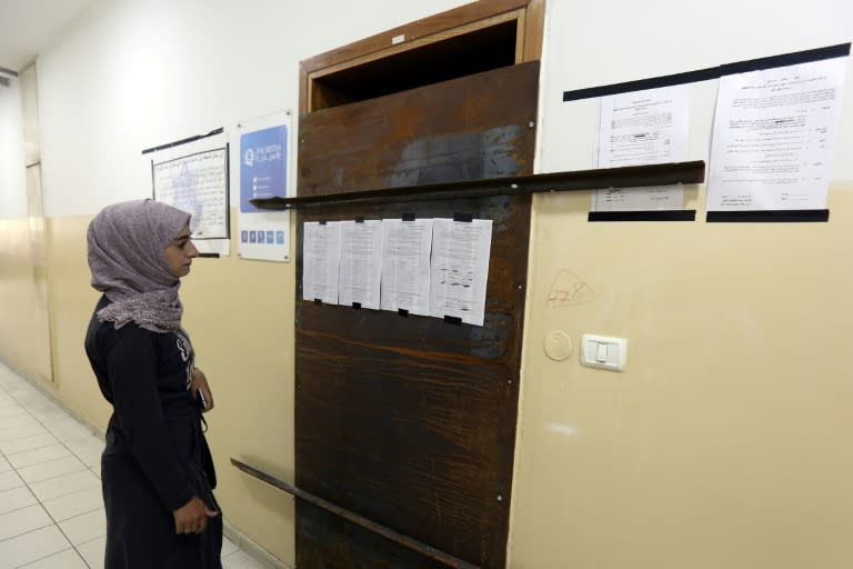 An employee of Palmedia reads a poster placed by Israeli troops on the doors of their office in the West Bank city of Nablus on October 18, 2017