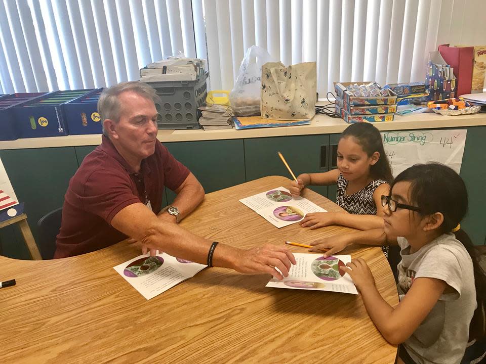 A Read With Me volunteer works with students.