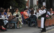 A waiter takes a photo in a restaurant in Covent Garden in London, Tuesday, Sept. 22, 2020. British Prime Minister Boris Johnson has slammed the brakes on the country's return to offices, saying people should work from home if possible to help slow the spread of the coronavirus. Johnson on Tuesday announced a package of new restrictions, including a requirement for pubs, restaurants and other hospitality venues in England to close between 10 p.m. and 5 a.m. (AP Photo/Frank Augstein)