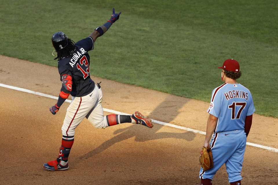 Atlanta Braves' Ronald Acuna Jr., left, reacts past Philadelphia Phillies first baseman Rhys Hoskins after hitting a two-run home run off relief pitcher Trevor Kelley during the sixth inning of the second baseball game in a doubleheader, Sunday, Aug. 9, 2020, in Philadelphia. (AP Photo/Matt Slocum)