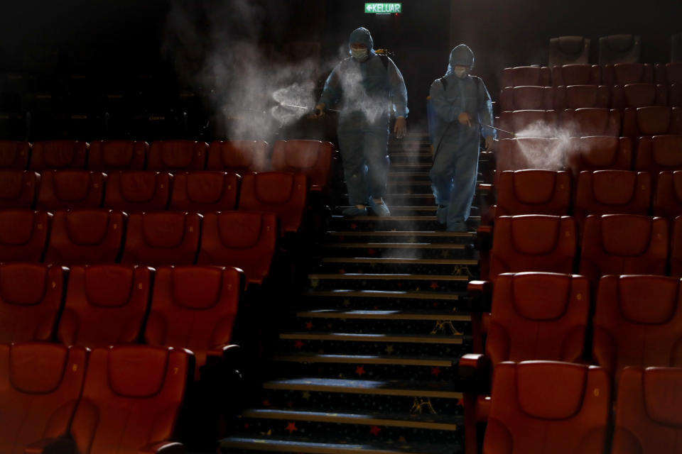 Cinema staff spray disinfectant in a theater to prepare for reopening on July 1 in Kuala Lumpur, Malaysia, on Friday, June 26, 2020. Malaysia entered the Recovery Movement Control Order (RMCO) after three months of coronavirus restrictions. (AP Photo/Vincent Thian)