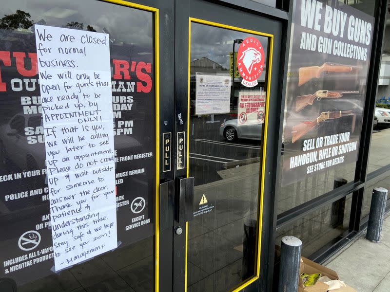 FILE PHOTO: A notice is seen outside a shuttered gun store in Long Beach, California, following a “stay-at-home” order issued by Governor Gavin Newsom