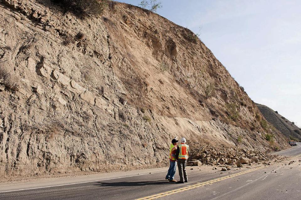 A CalTrans worker and a geologist look at a rock wall where a rockslide closed Carbon Canyon Road near Carbon Canyon Regional Park in Brea, Calif., on Saturday, March 29, 2014 after an earthquake hit Orange County Friday night. More than 100 aftershocks have rattled Orange County south of Los Angeles where a magnitude-5.1 earthquake struck Friday. Despite the relatively minor damage, no injuries have been reported. (AP Photo/The Orange County Register, Ken Steinhardt) MAGS OUT; LOS ANGELES TIMES OUT