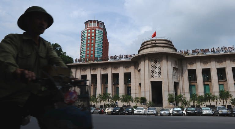 A cyclist rides past the State Bank of Vietnam headquarters in Hanoi on July 6, 2012. Opaque, corrupt, inefficient -- Vietnam's state-run companies are used to criticism, but now they stand accused of creating a systemic economic crisis which the communist regime cannot fix