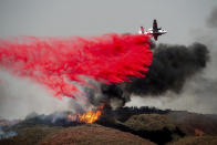 FILE - In this July 30, 2018, file photo, an air tanker drops retardant on a wildfire burning near Lakeport, Calif. California is in the midst of another devastating year of wildfires and finding the causes for the worst of them can be critical to identifying better fire-prevention techniques. But often investigators can’t figure out a cause. (AP Photo/Noah Berger, File)