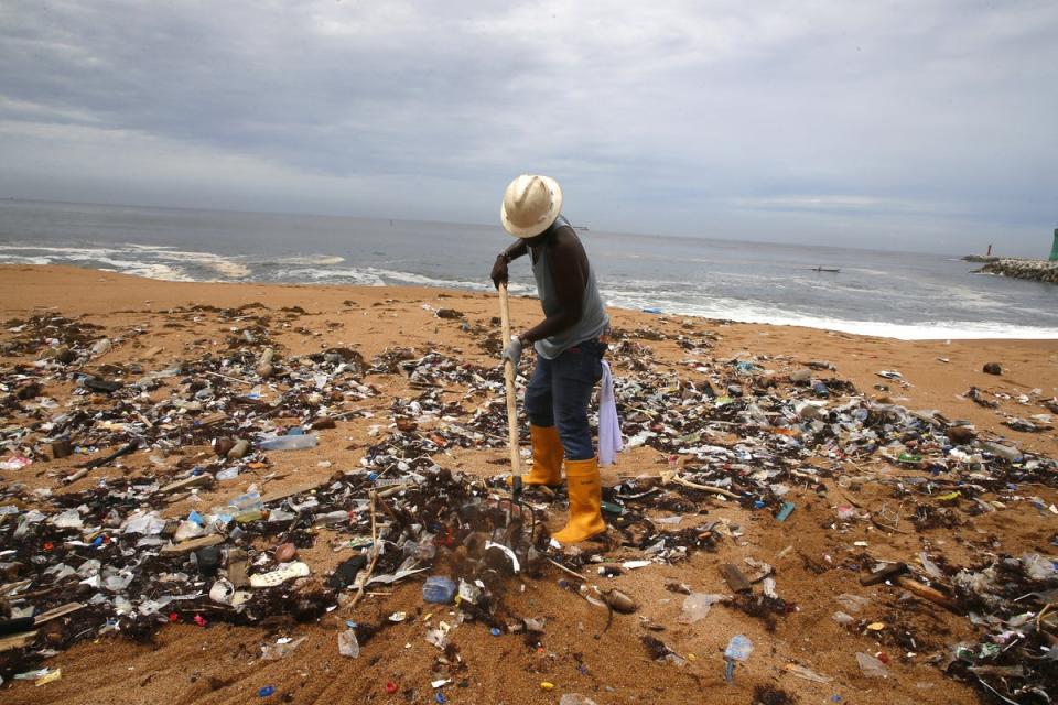 A member of an environmental NGO cleans plastic debris from Vridi beach in Abidjan, Ivory Coast (EPA)